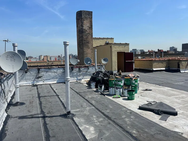 Workers applying reflective roof coating on a commercial building in Nassau County