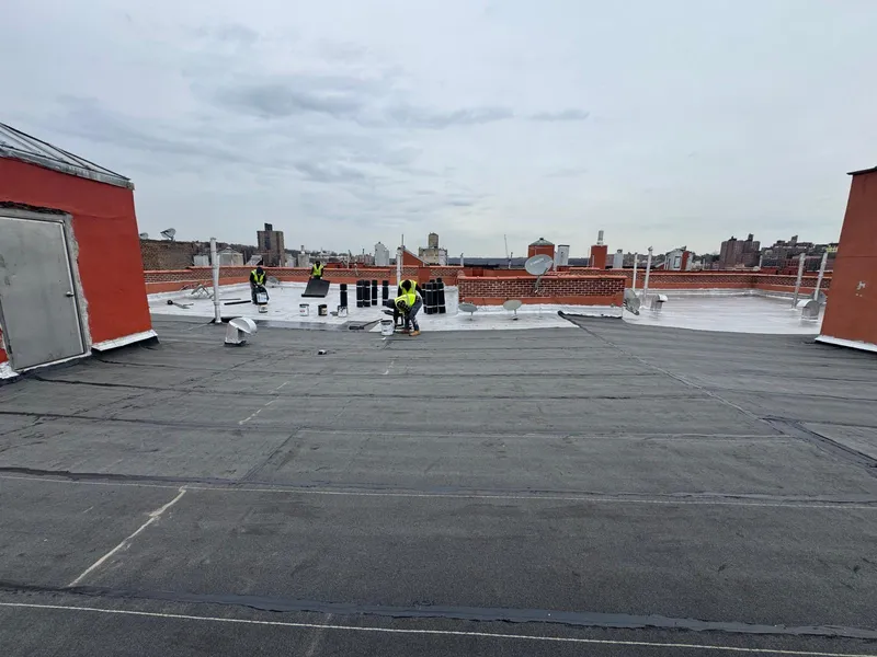 Rooftop repair work with Nassau County skyline in background